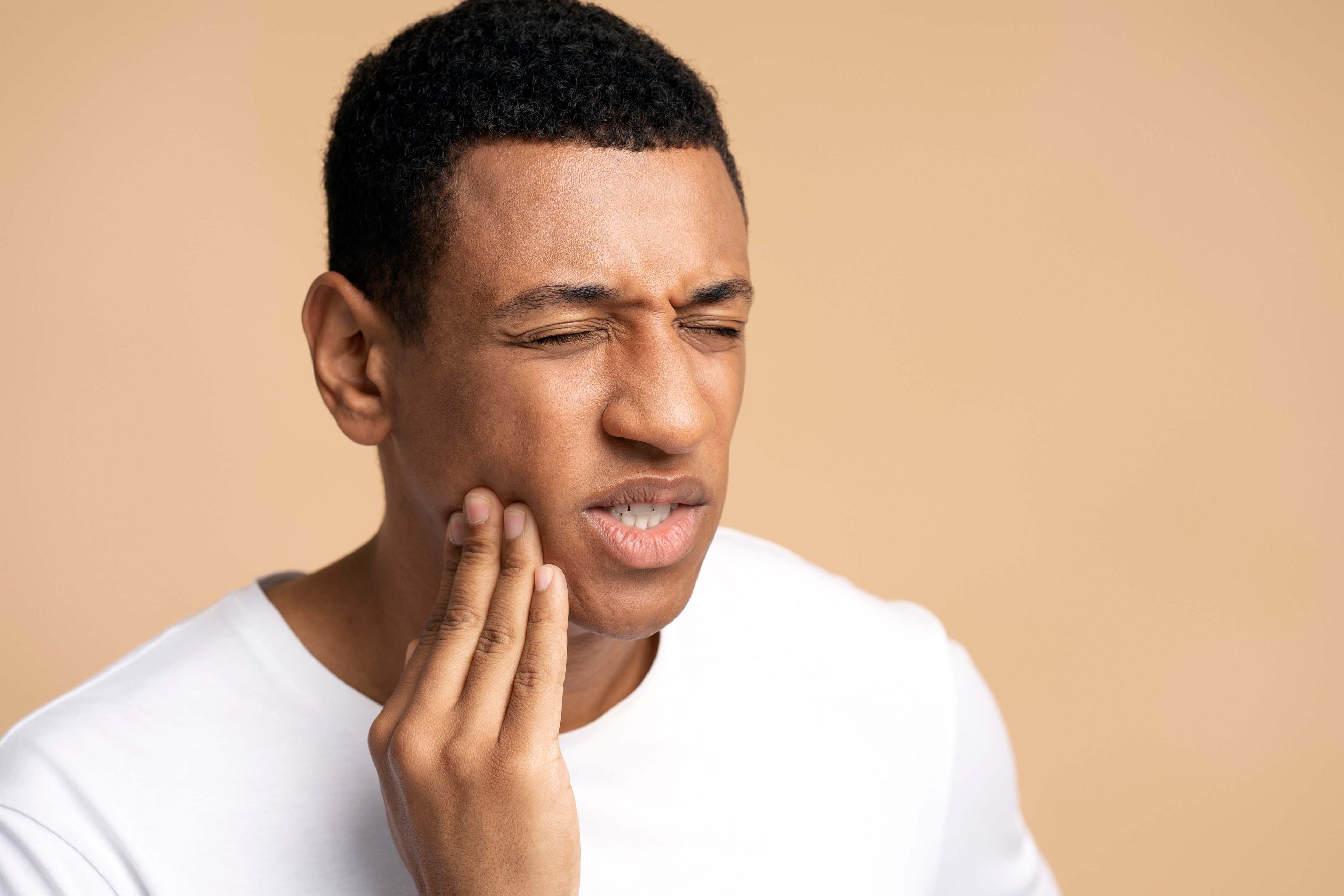man feeling pain holding his jaw